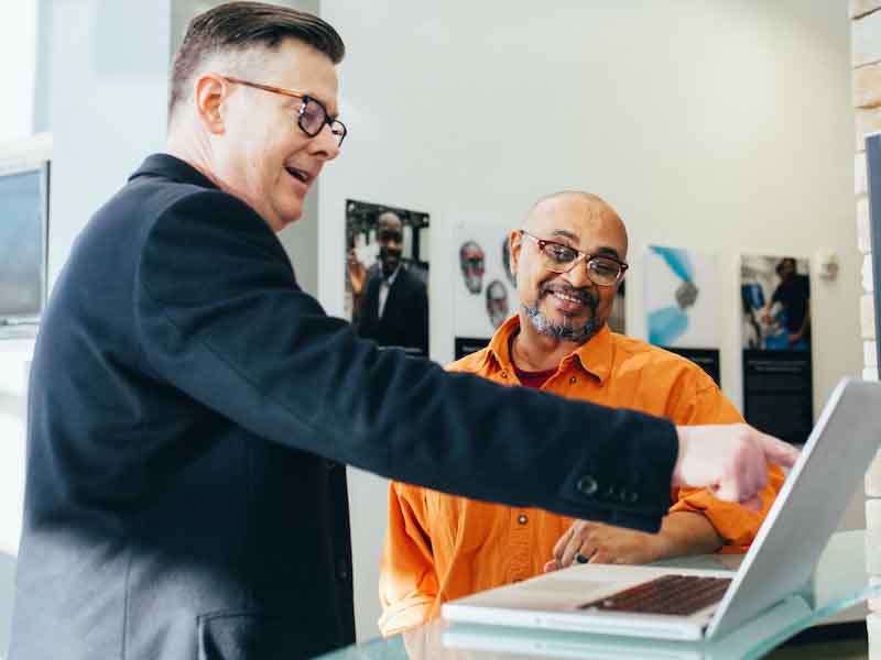 two men talking at a computer