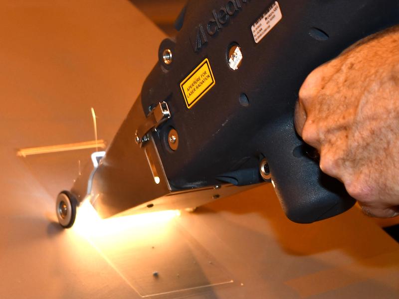 A close-up of a laser ablation system in use to remove coatings from an aircraft engine can. 