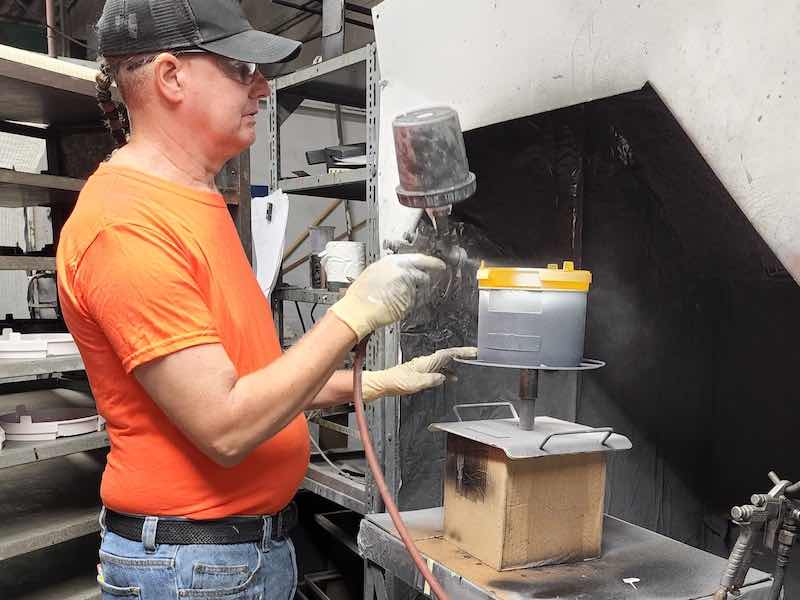 Tim Harris spraying parts in a booth.